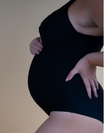 Side view of pregnant mother wearing black one-piece nursing swimsuit 