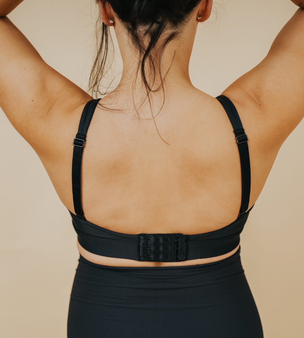 Back view of active mom wearing black nursing sports bra with crossover straps