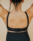 Back view of active mom wearing black nursing sports bra with crossover straps