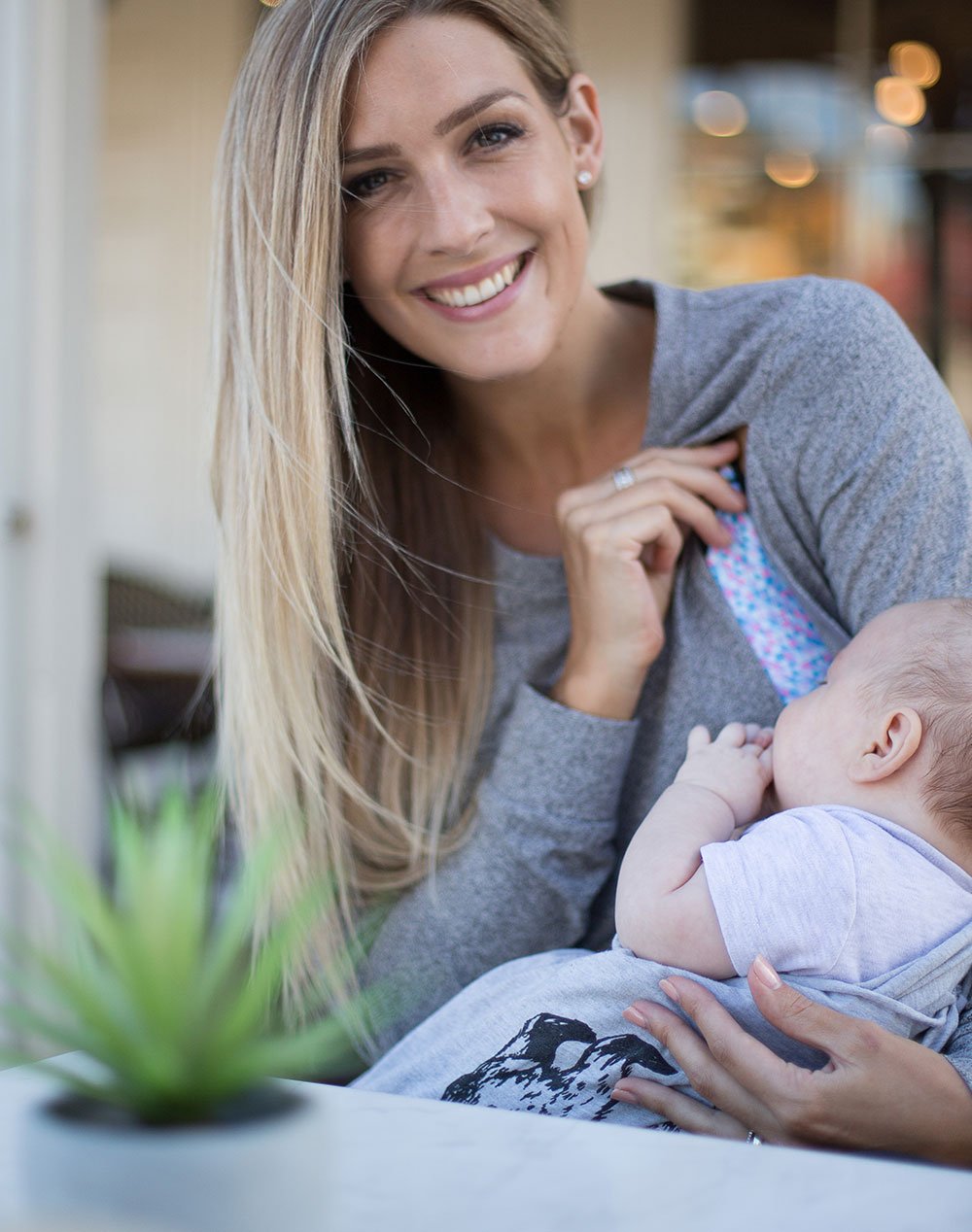 active mum breastfeeding in a grey crew neck maternity top